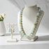 Necklace and earrings on a white stand with a marble background