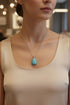 Turquoise teardrop pendant on a chain against a white background