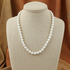 Pearl necklace on a beige mannequin bust with a brown fabric background